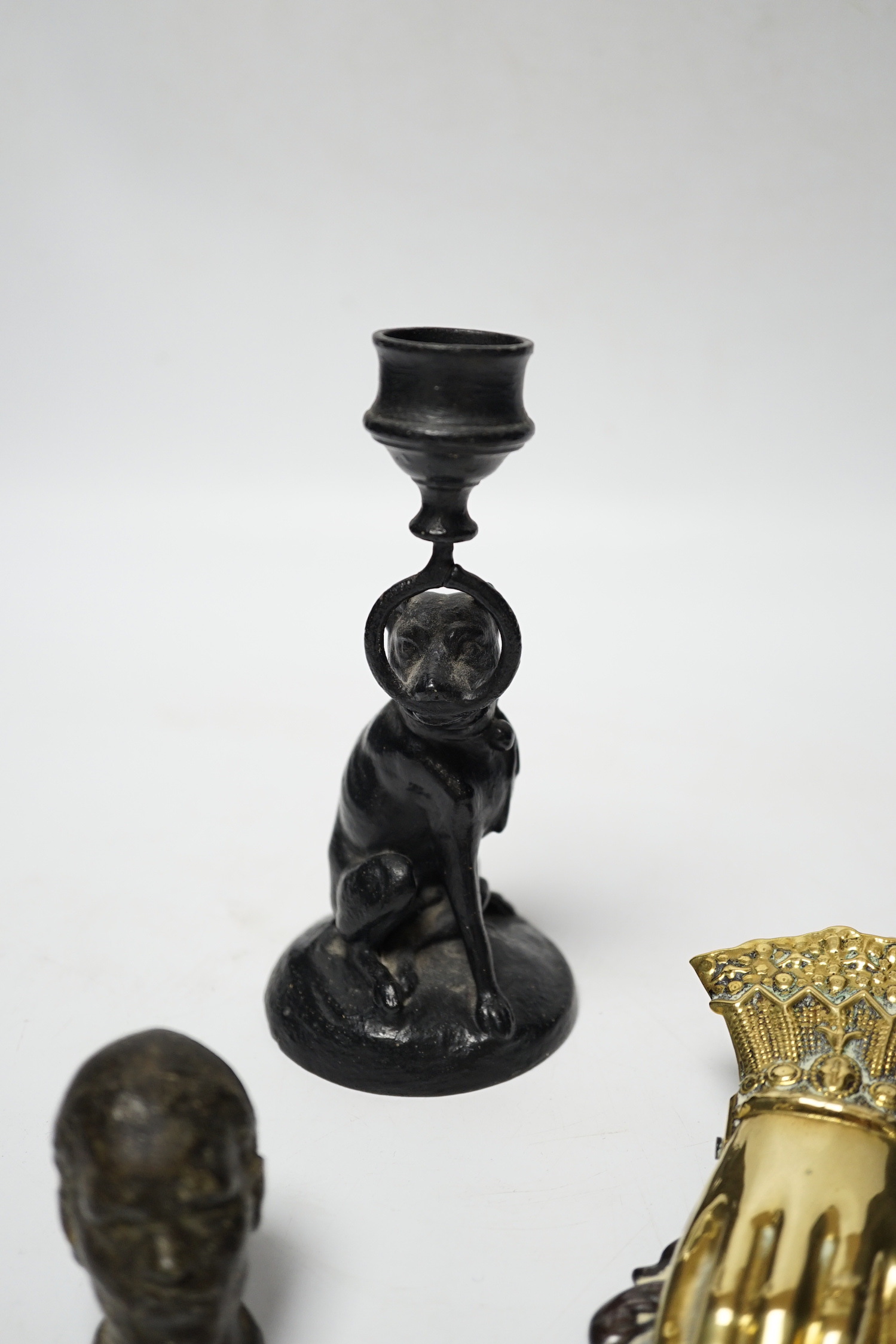 A Victorian brass hand paper clip, a small bronze tribal head and novelty dog candlestick, tallest 15cm high